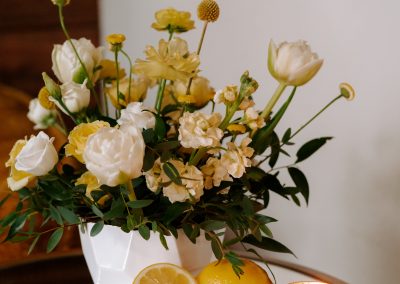 A pot of flowers sitting on a table with some lemons.